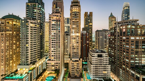 A high-rise urban skyline with multiple buildings, including a prominent hotel with a rooftop pool and a distinctive dome structure. - Urbana Langsuan Hotel (Bangkok)