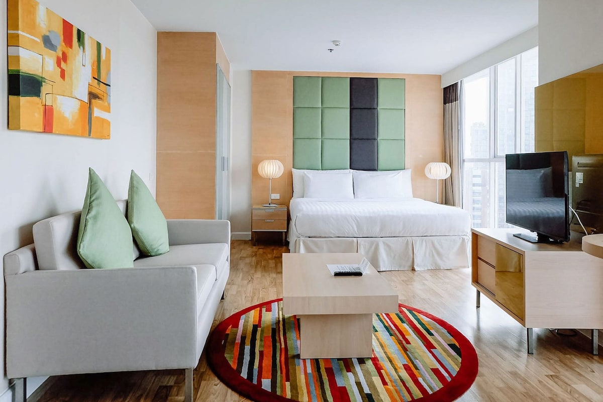 Une chambre d’hôtel moderne équipée d’un lit, d’un canapé, d’une télévision et d’un bureau.