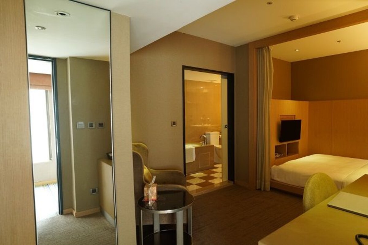 Een hotelkamer met een bed, bureau, stoel, televisie en spiegel.