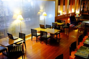 Eine moderne Hotelhalle mit Holzboden, mehreren Tischen und Stühlen sowie gedämpfter Beleuchtung.