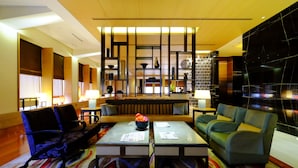 Een moderne hotellobby met zithoeken, een receptiebalie en een decoratieve wand met planken.