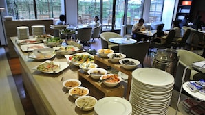 Een buffetopstelling met diverse gerechten en een stapel borden.