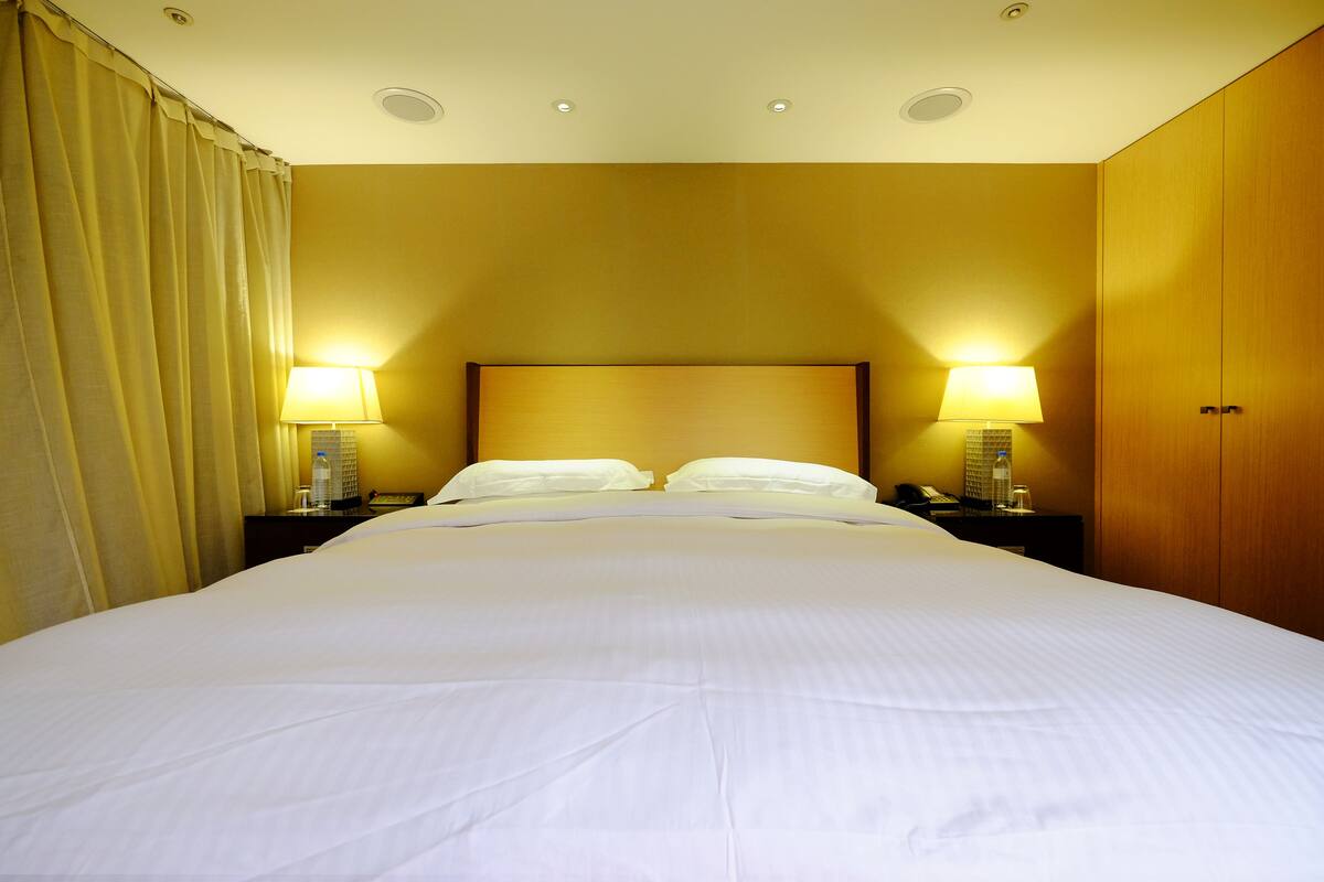 Een hotelkamer met een groot bed, twee bedlampen en een houten garderobe.
