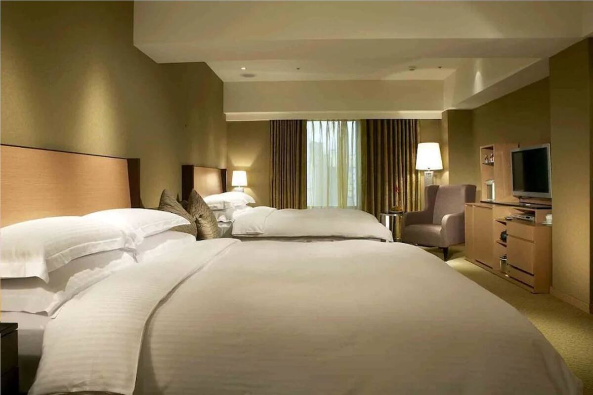 Een hotelkamer met twee bedden, een televisie, een bureau en een stoel.