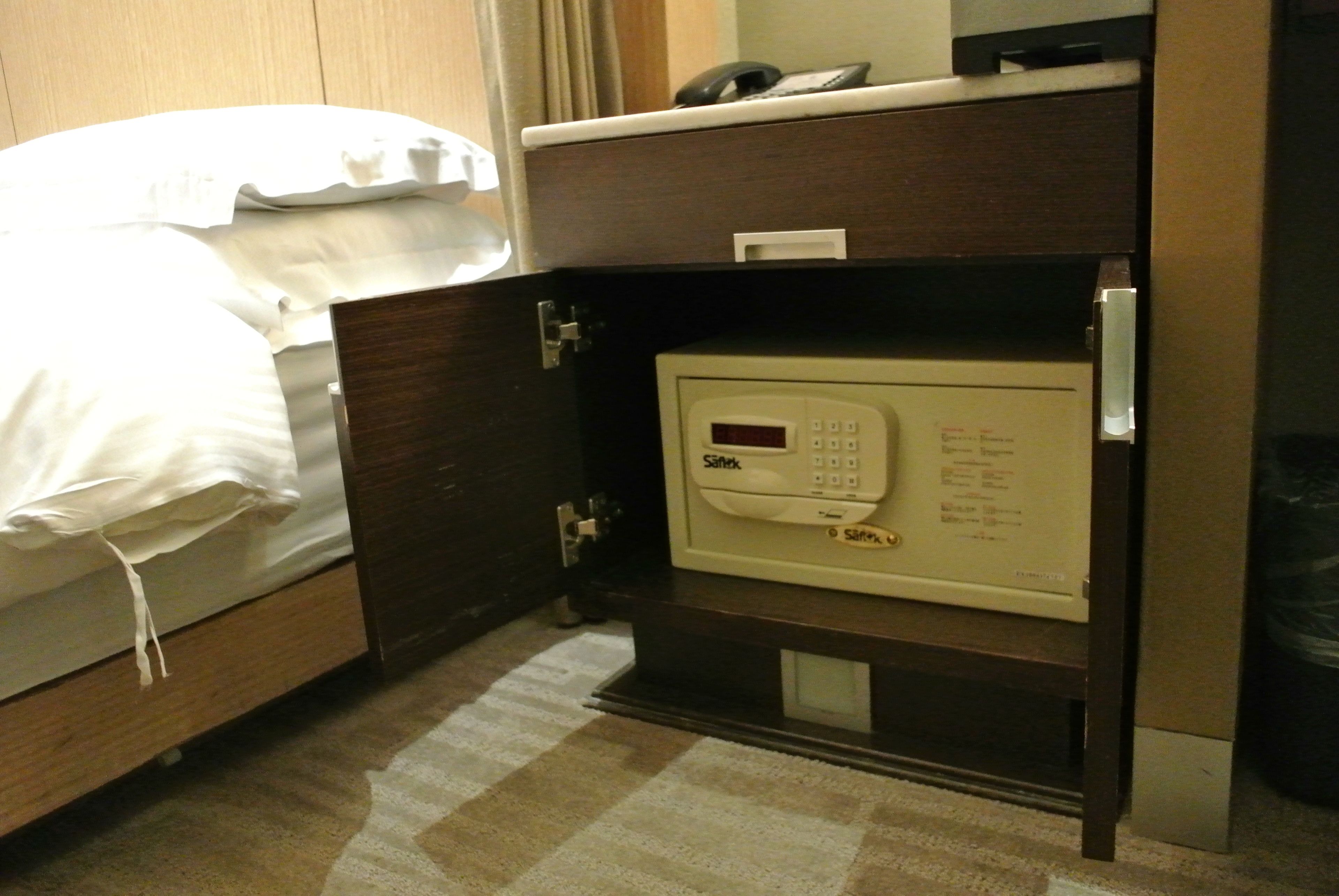 Una habitación de hotel con una cama, un minibar y una caja fuerte.