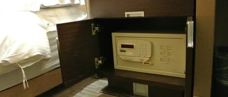 Una habitación de hotel con una cama, un minibar y una caja fuerte.