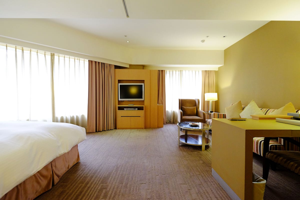 Een hotelkamer met een groot bed, een bureau met stoel, een televisie en een bank.