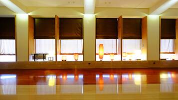 A spacious room with large windows, a polished wooden floor, and a table with lamps.