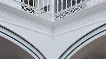 A white balustrade with intricate designs, a white ceiling, and a white column with a green stripe.