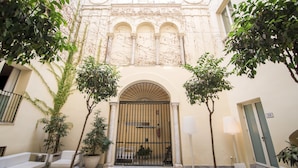 A courtyard with a gated entrance, potted plants, outdoor seating, and a lamp post. - Petit Palace Santa Cruz (Seville)