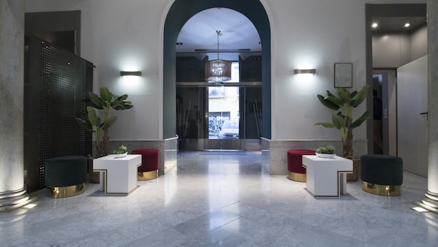 A modern lobby with a marble floor, a central archway, and symmetrical lighting. - Petit Palace Santa Cruz (Seville)