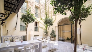A courtyard with outdoor seating, a dining area, and a gate. - Petit Palace Santa Cruz (Seville)