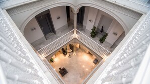 A spacious atrium with a central seating area, columns, and a balcony with railings. - Petit Palace Santa Cruz (Seville)