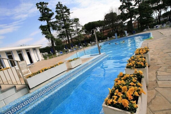 Una piscina techada, una piscina al aire libre, sombrillas