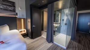 A modern hotel room with a bed, a glass shower enclosure, and a visible bathroom. - Grand Times Hotel Quebec City Airport (L'Ancienne-Lorette)