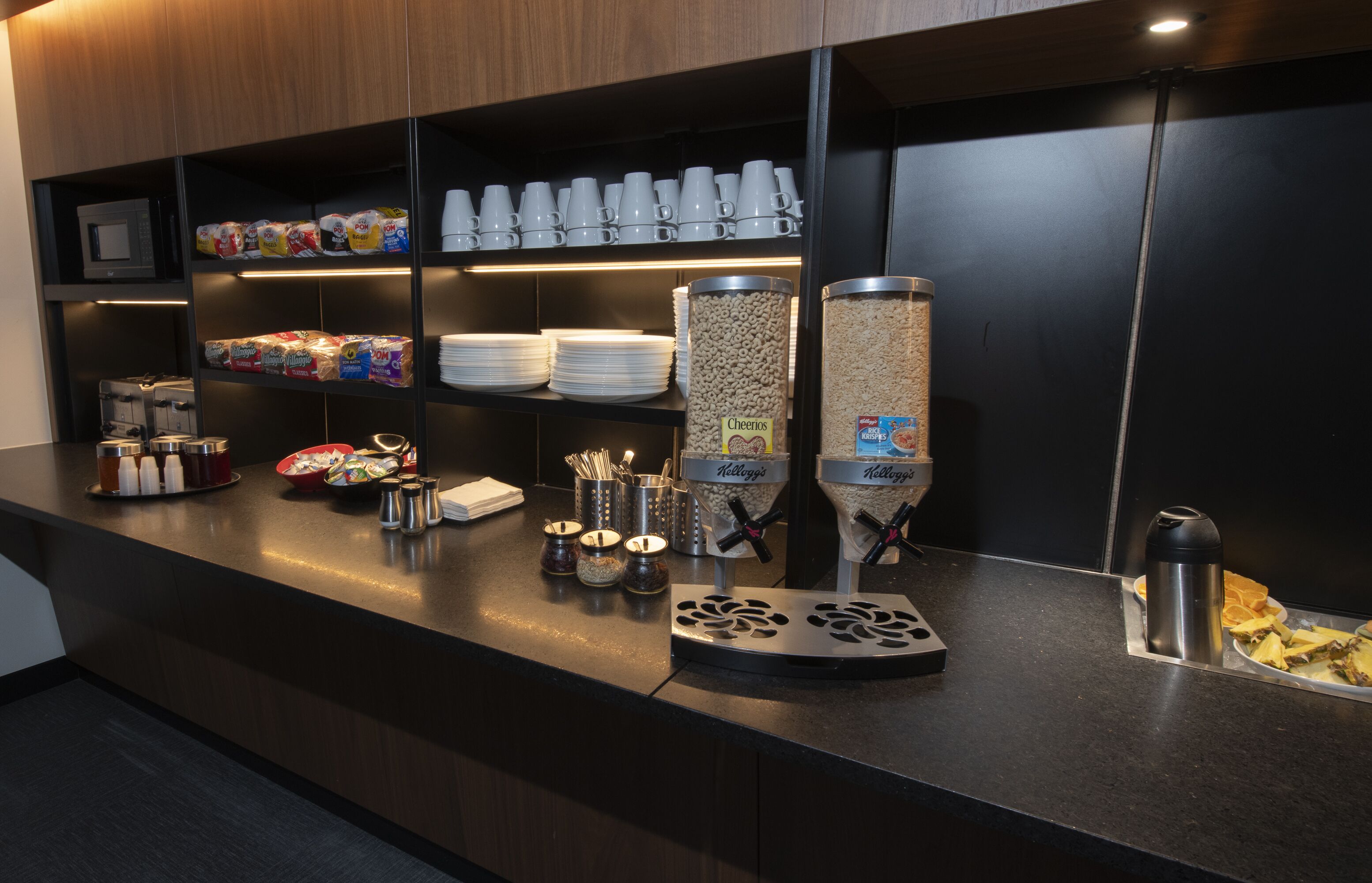 Zona de buffet amb diversos aliments, com ara cereals, condiments i una màquina de cafè.