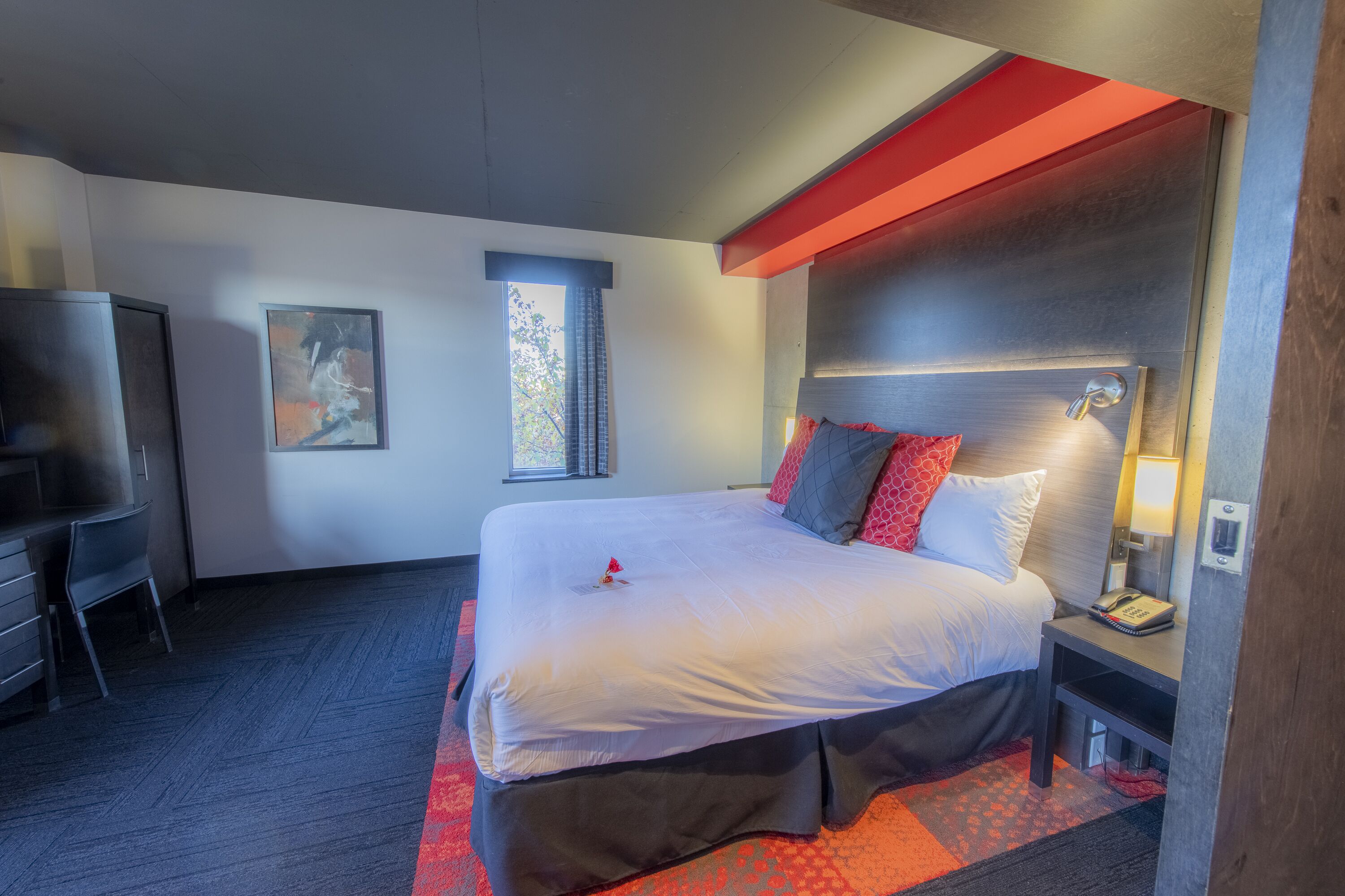 A modern hotel room with a large bed, a desk, and a television.