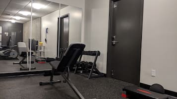 Una palestra con attrezzature per esercizi, uno specchio e una porta.