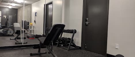 Un gimnasio con equipo de ejercicio, un espejo y una puerta.