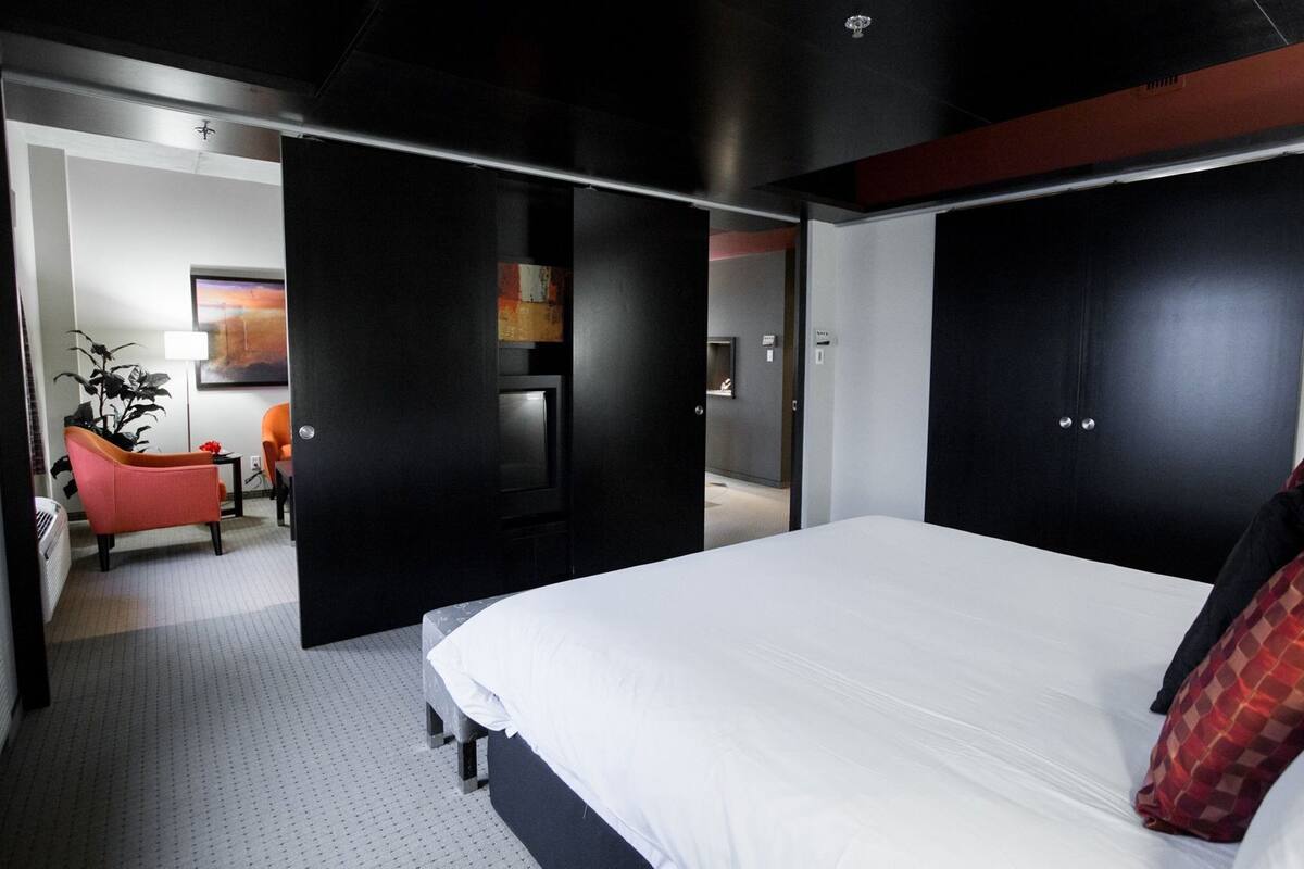 Una habitación de hotel moderna con una cama grande, un escritorio, una silla y un armario.