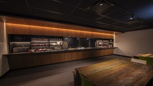 A modern kitchen area with a long counter, various appliances, and a seating area with a wooden table and chairs. - Grand Times Hotel Quebec City Airport (L'Ancienne-Lorette)