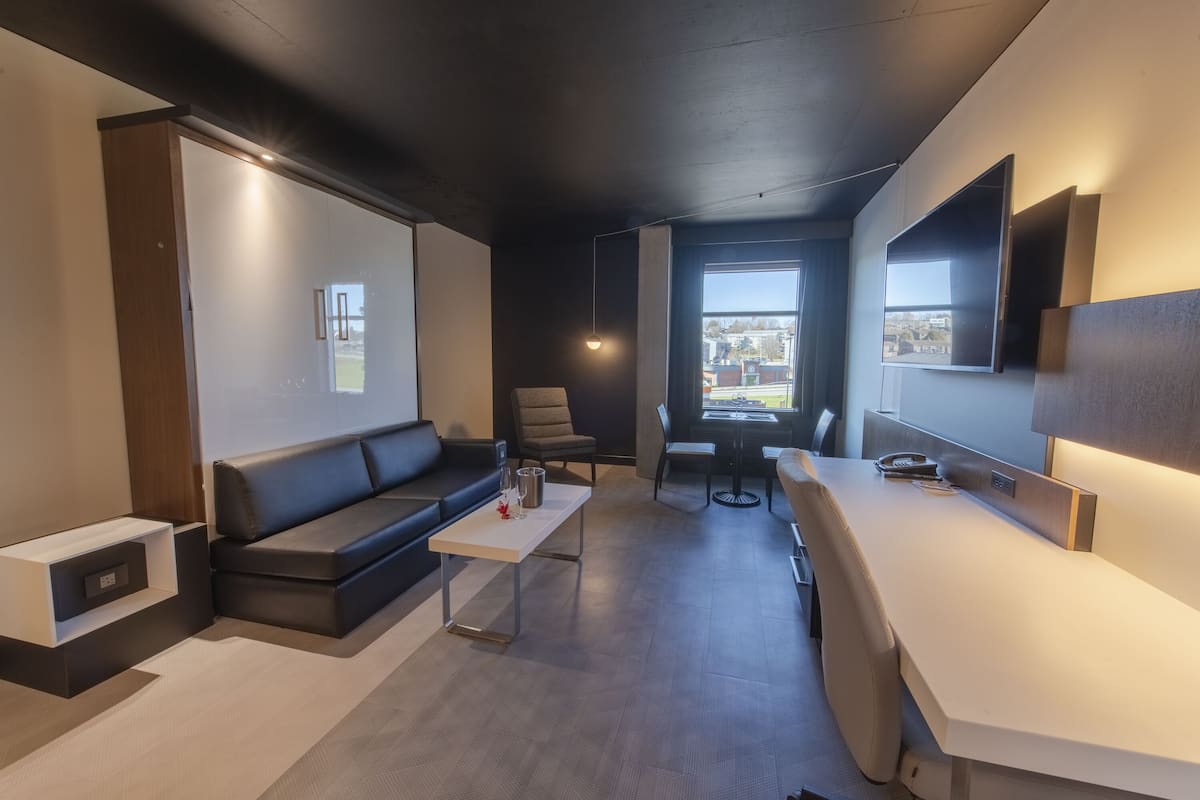 Una sala de estar moderna con un sofá, una mesa de centro, un televisor y un ventanal con vista a la ciudad.