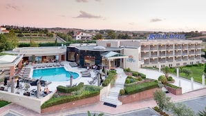 A hotel with a swimming pool, outdoor seating, and a landscaped garden.