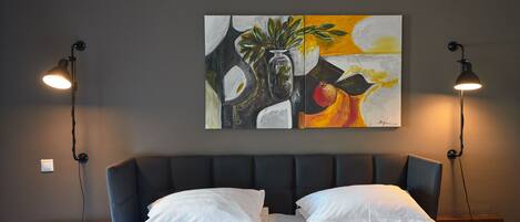 Una habitación de hotel con una cama grande, dos lámparas de noche, una mesita de noche y un cuadro en la pared.