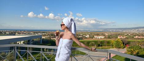 A person on a balcony with a view of a cityscape and greenery.