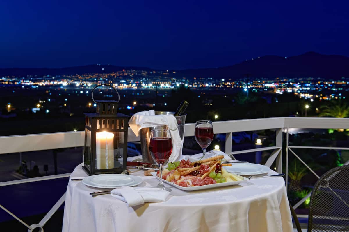 A table set for two with a view of a cityscape at night.