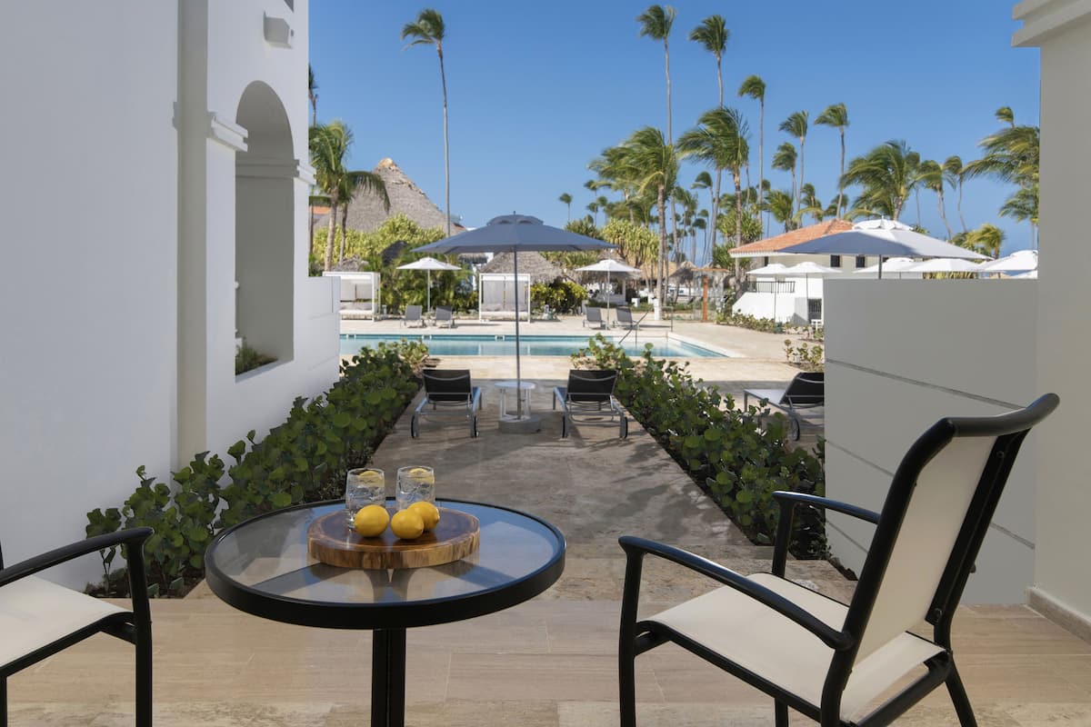 A poolside area with lounge chairs, a table with lemons, and a view of the pool and palm trees.