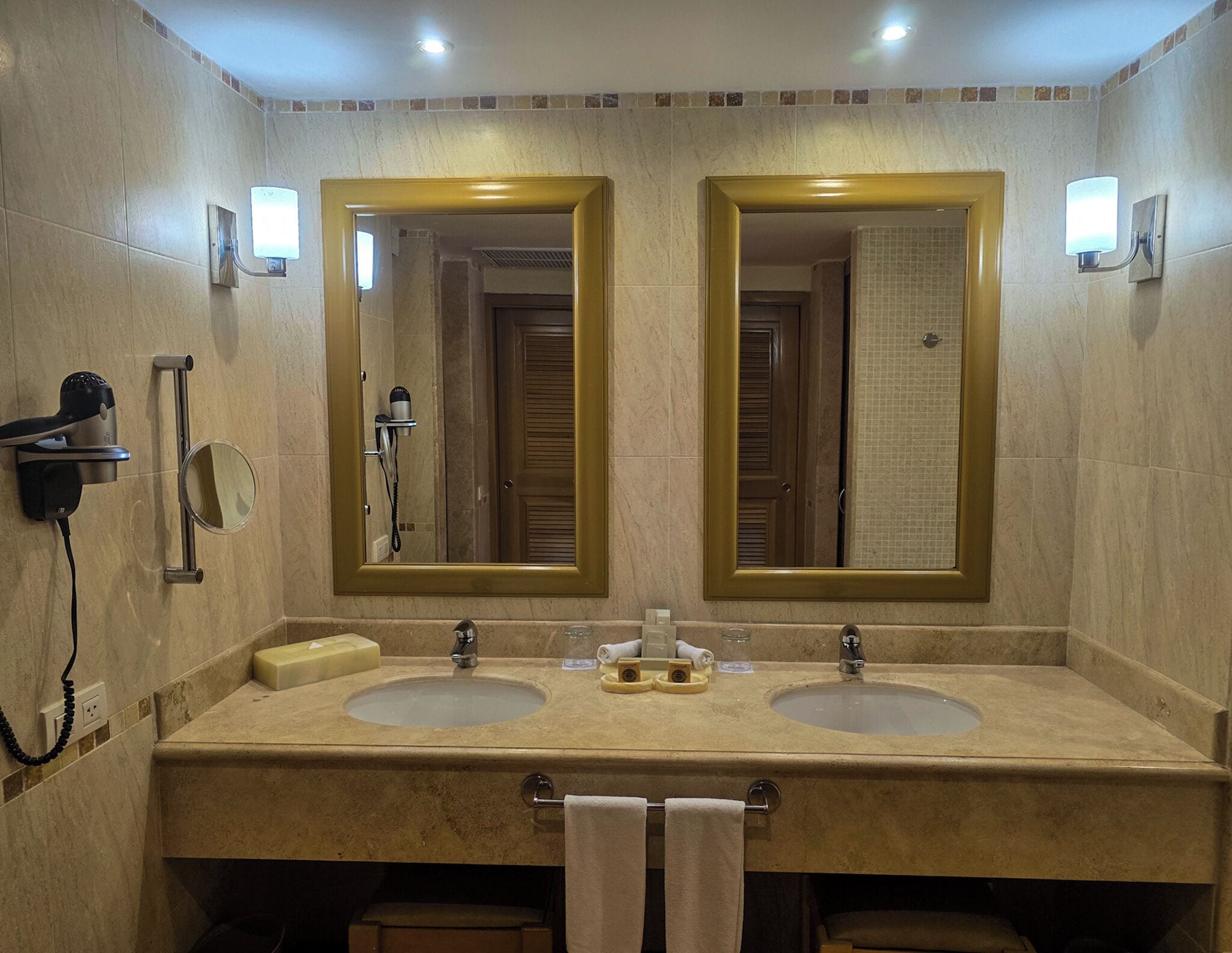 A bathroom with two sinks, a hairdryer, and a mirror.