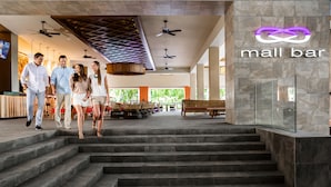 Un bar en un centro comercial con una decoración moderna, incluyendo una escalera que lleva a la zona del bar.