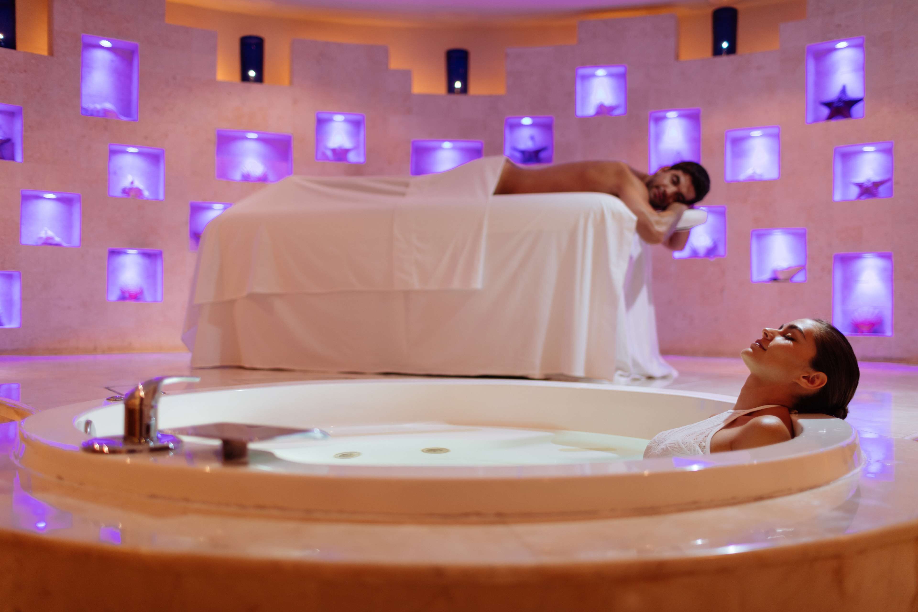 Un cuarto de spa con una bañera grande y una camilla de masaje.
