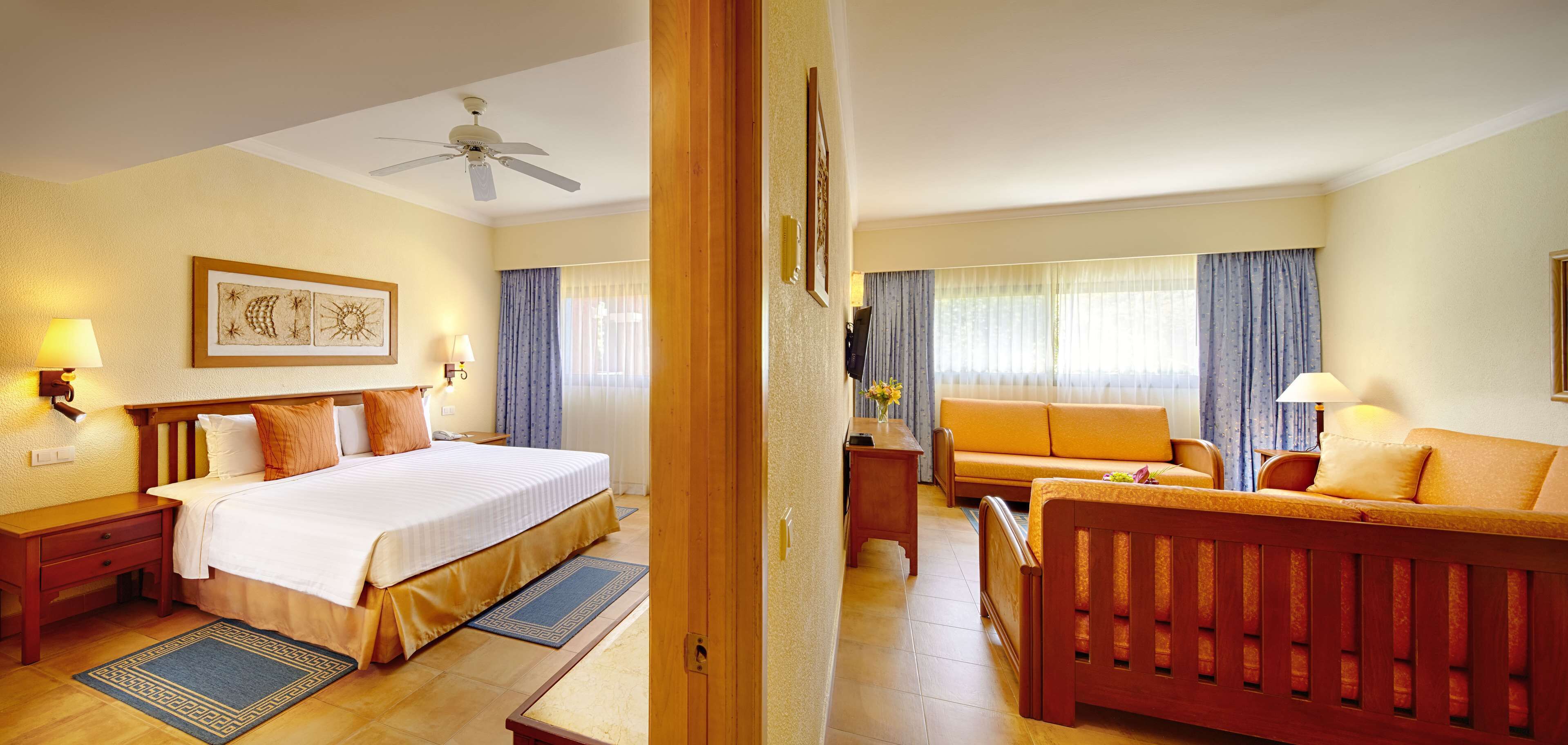 Una habitación de hotel con cama, sofá, escritorio y ventilador de techo.