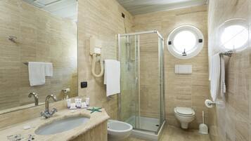 A modern bathroom with a glass-enclosed shower, a round mirror, a sink, and a toilet.