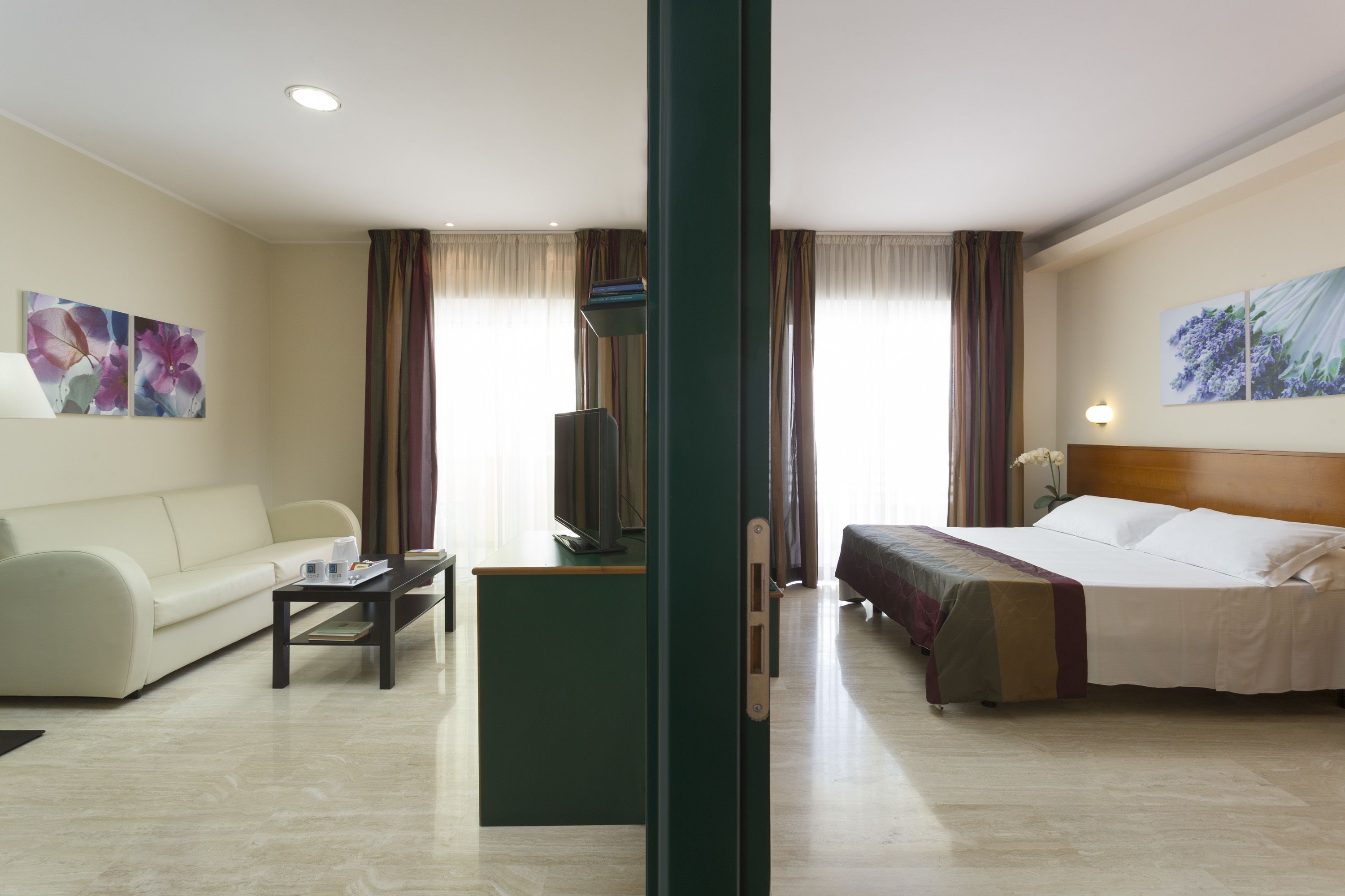 A hotel room with a bed, a sofa, a TV, and a coffee table.