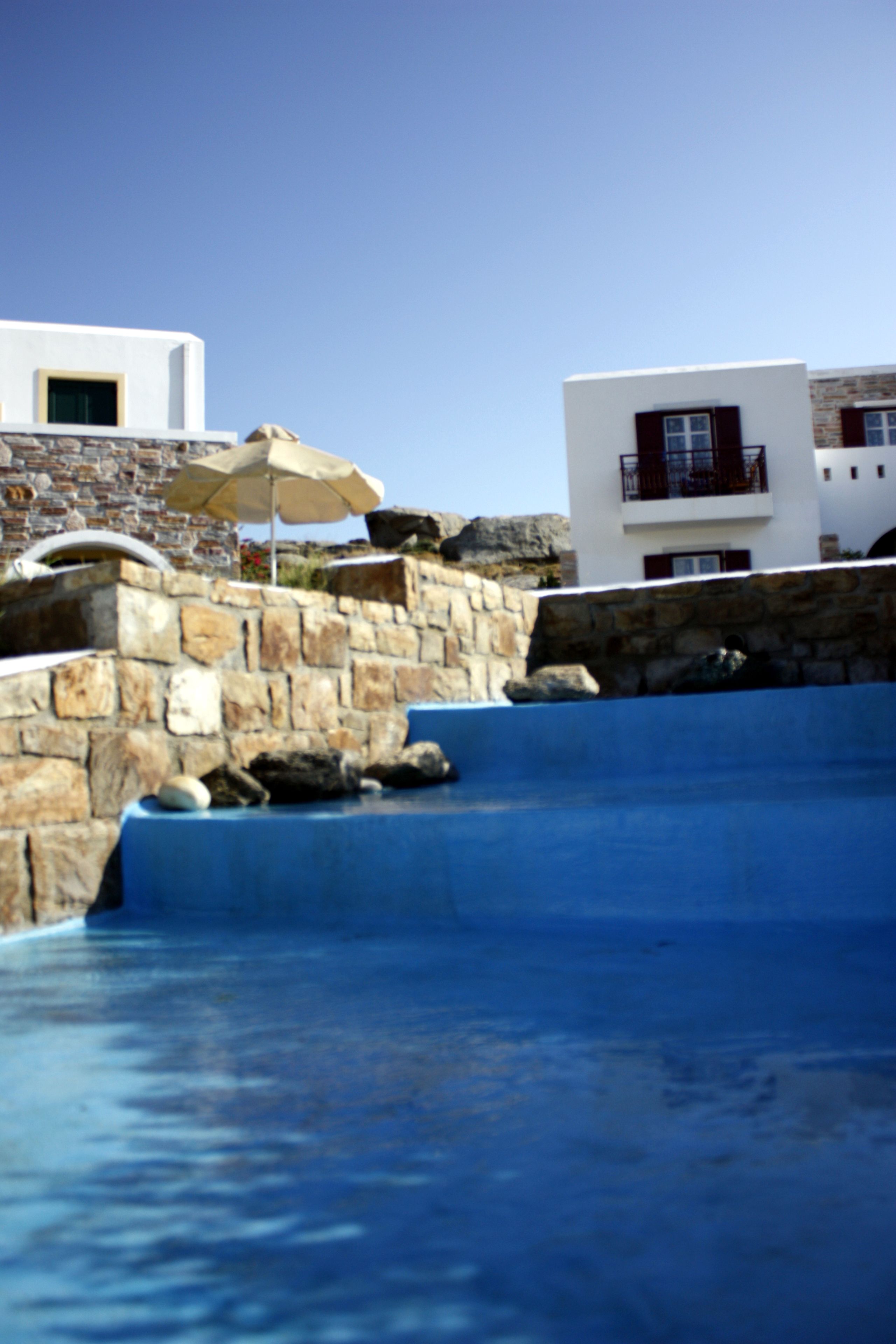 A swimming pool with a stone wall and a modern building in the background.