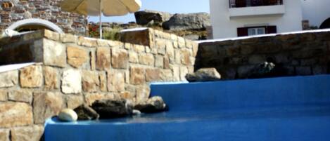 A swimming pool with a stone wall and a modern building in the background.