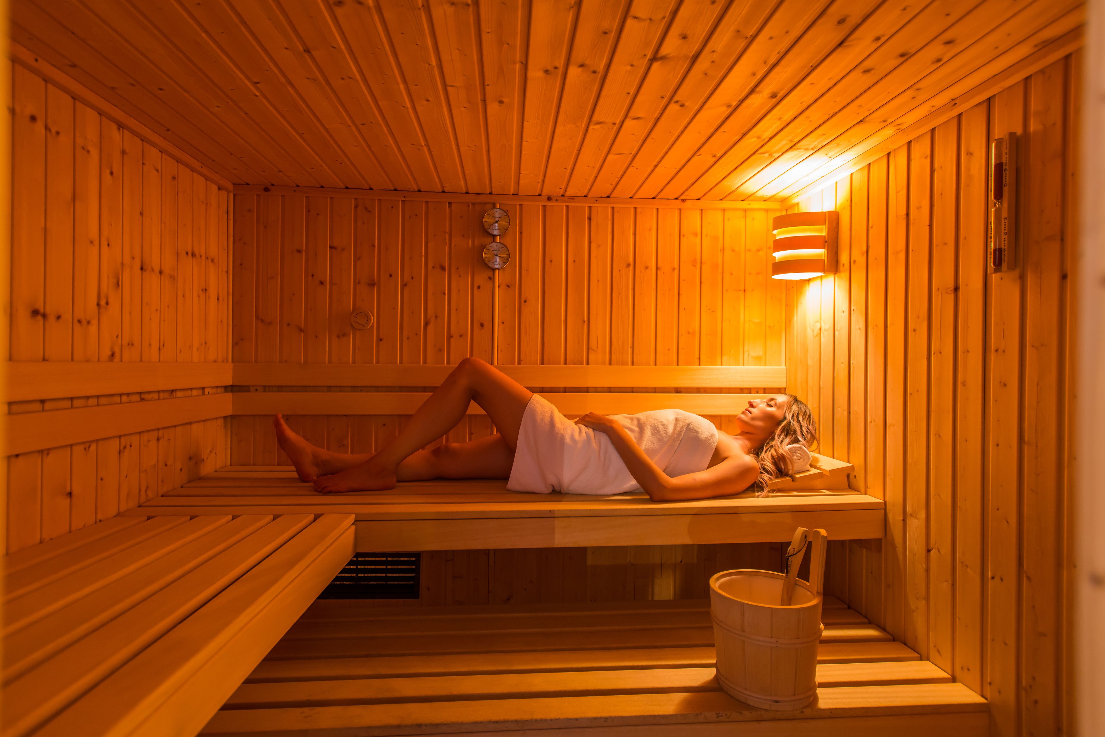 A sauna with wooden benches and a wall-mounted heater.
