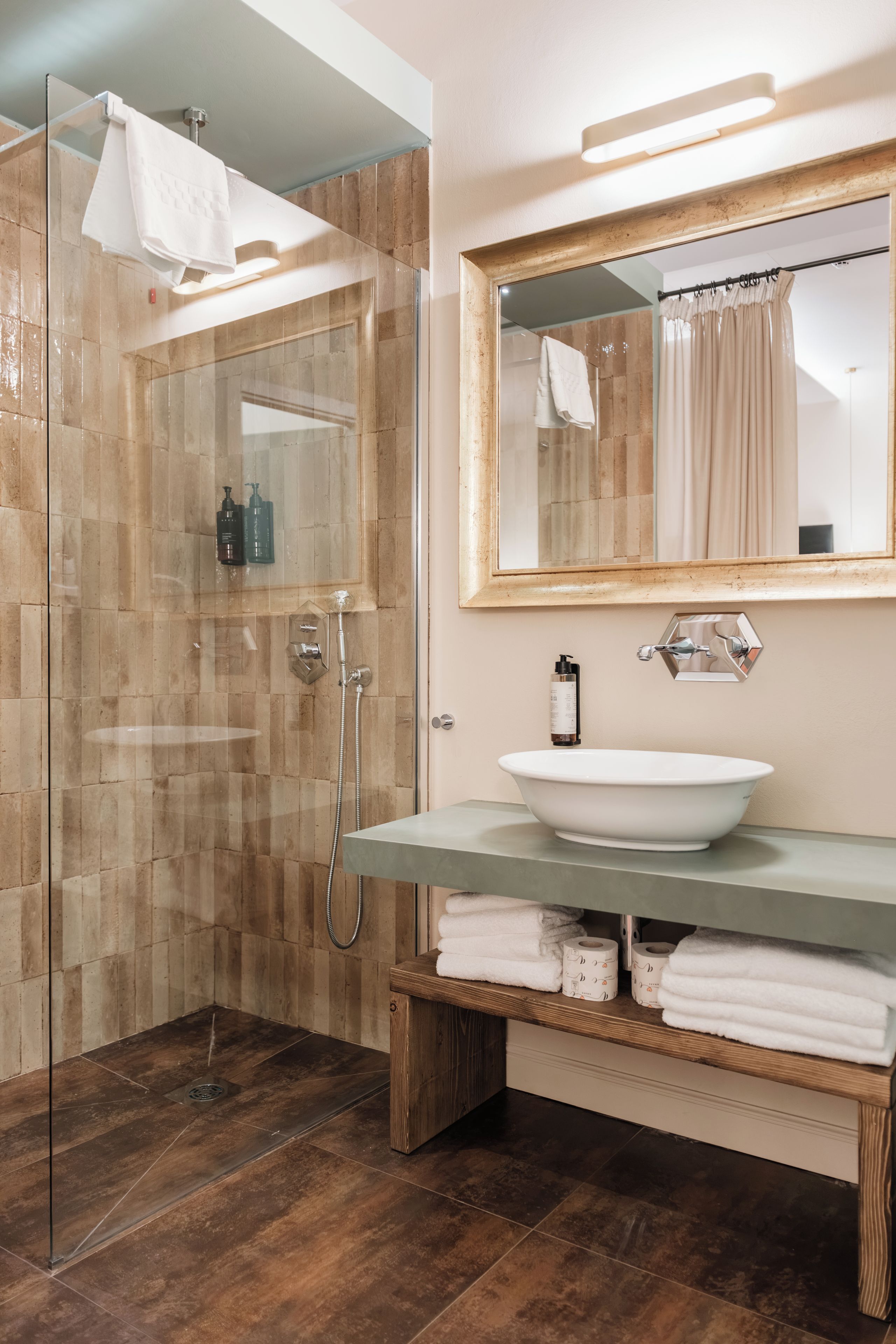 Une salle de bain moderne dotée d’une douche à parois de verre, d’un meuble-lavabo en bois avec un vasque en verre, et d’un miroir au-dessus du lavabo.