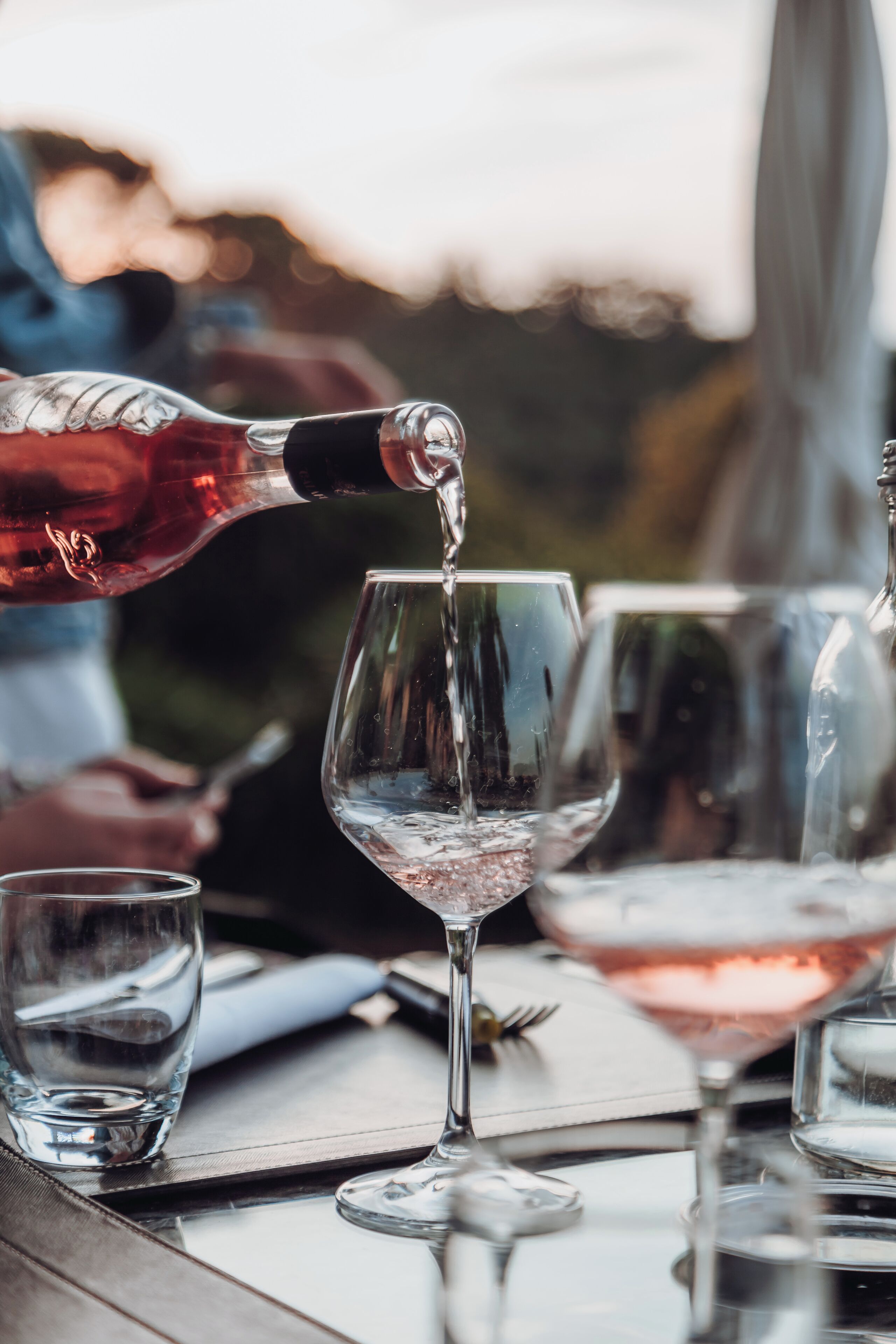 Ein Tisch mit mehreren Weingläsern und einer Flasche, aus der eines gefüllt wird.
