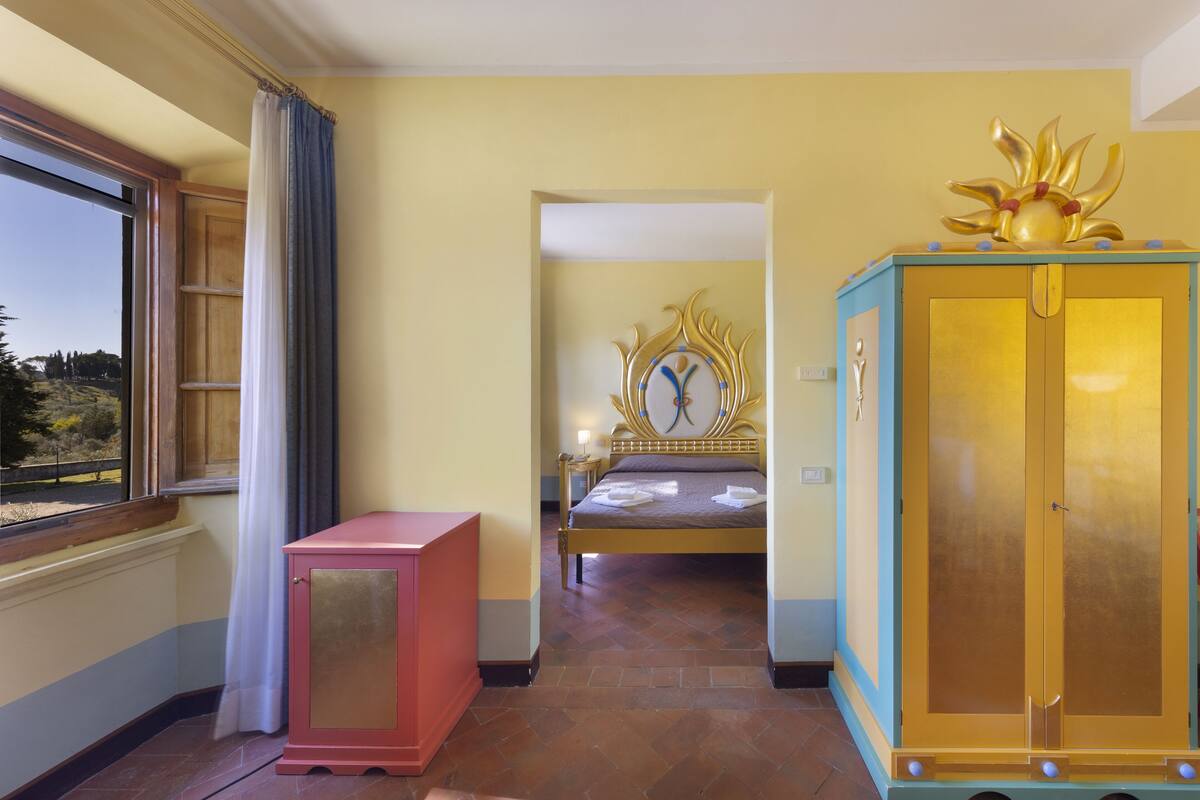 A bedroom with a bed, a wardrobe, and a window with curtains.