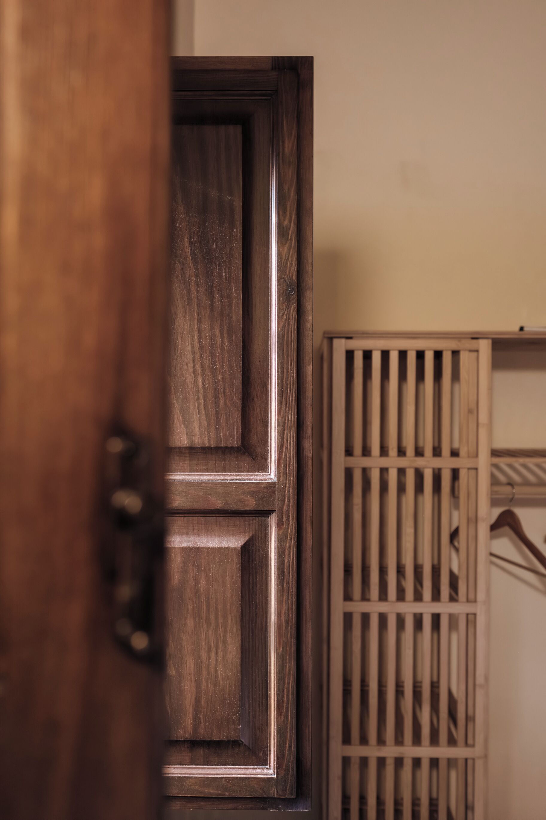 A wooden door with a handle, a wooden panel with vertical slats, and a wall-mounted rack with hanging items.