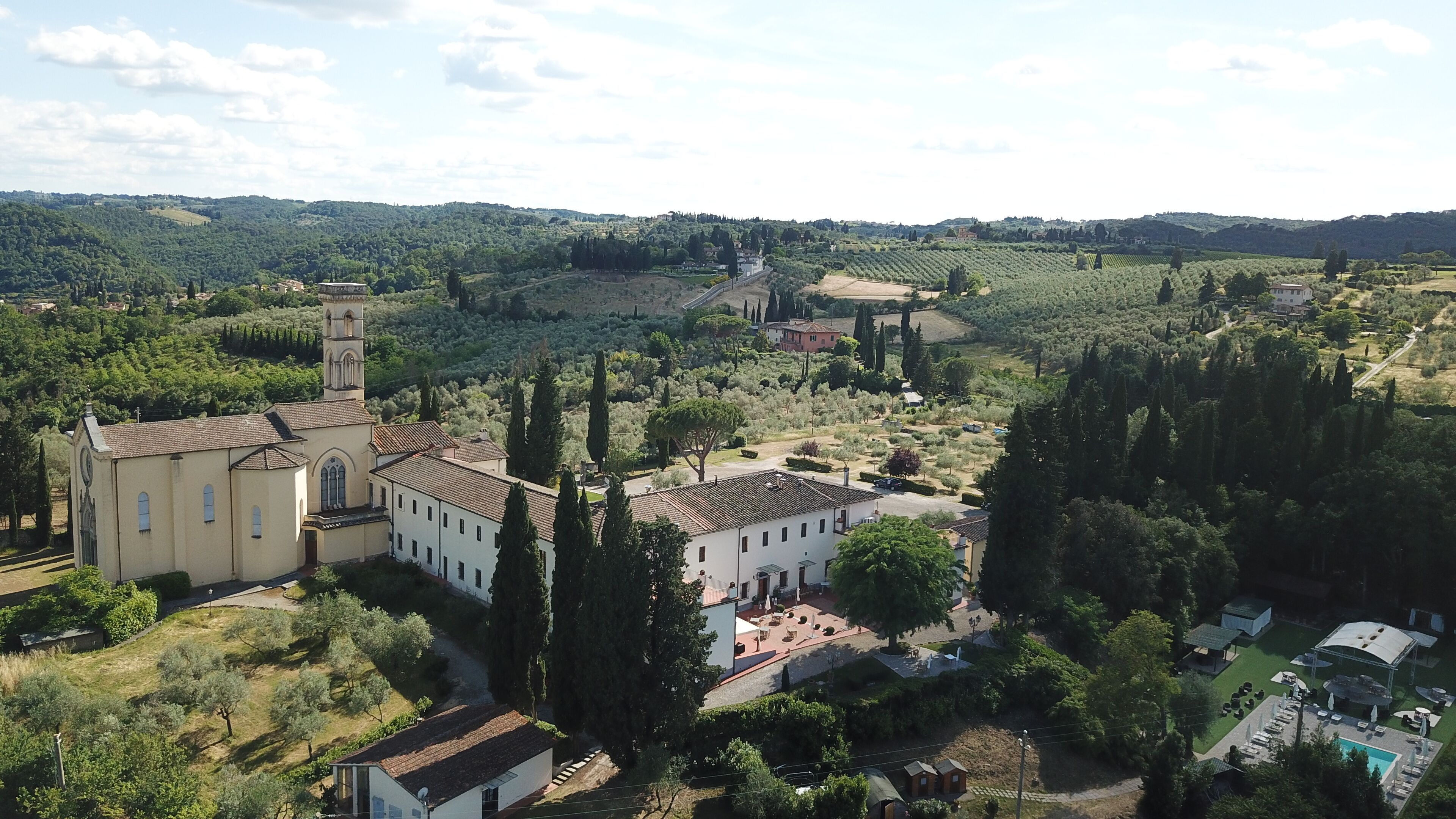 Paisaje rural con una iglesia, piscina y viñedos.