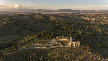 Une vue aérienne d’un bâtiment historique, entouré d’une végétation luxuriante et de collines ondoyantes.