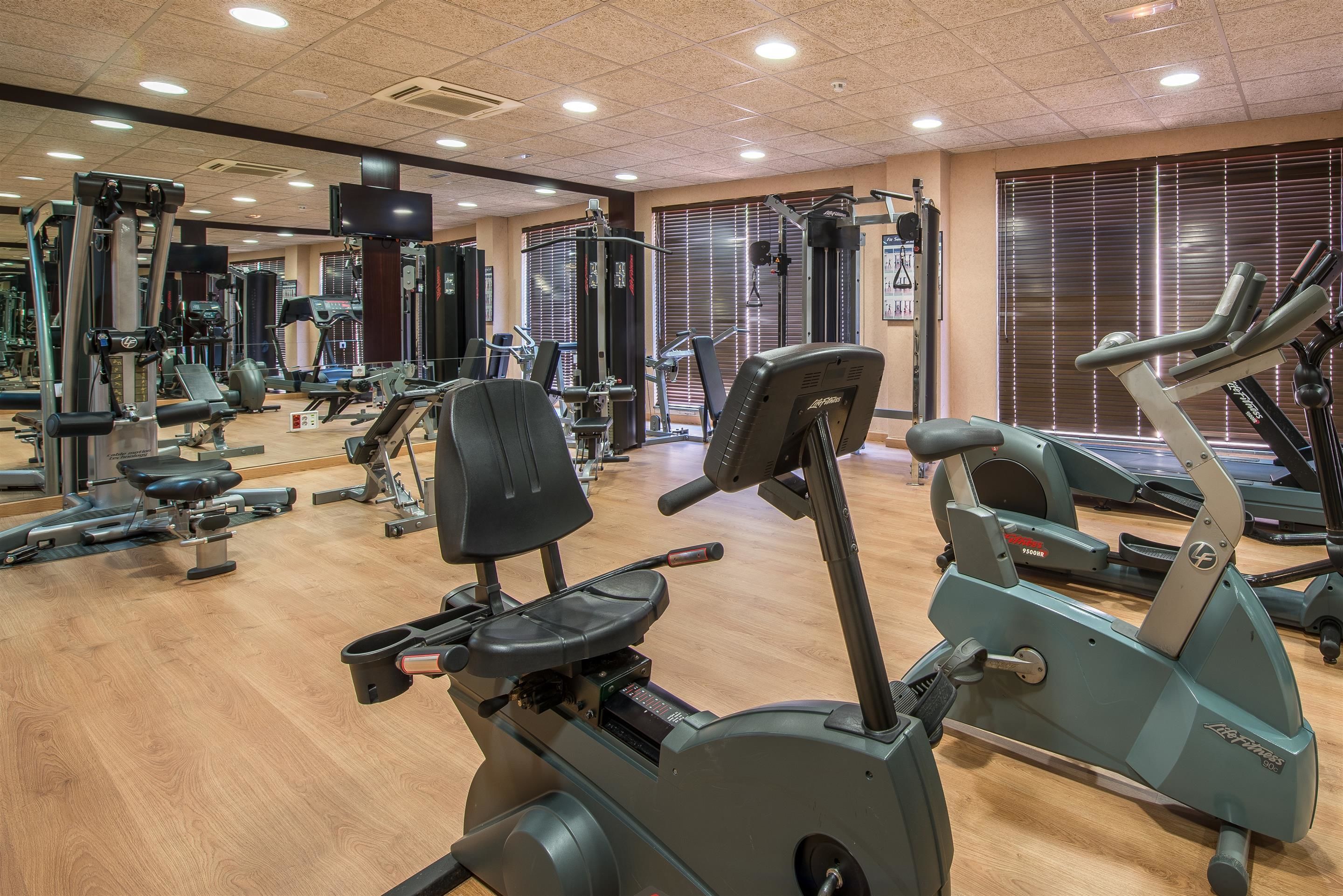 Ett gym med olika typer av träningsutrustning, inklusive löpband och styrketräningsmaskiner.