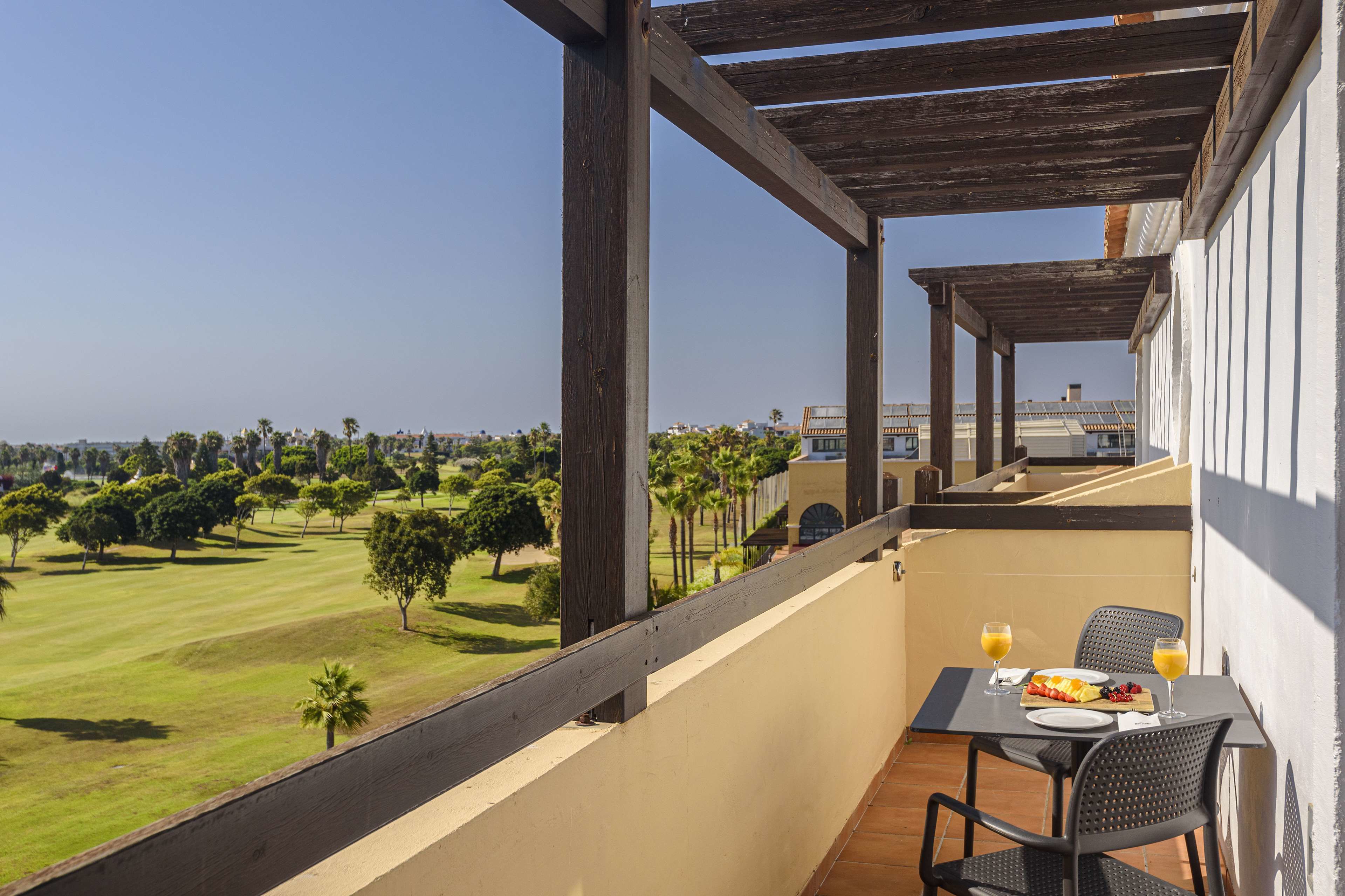 A balcony with a table set for two, overlooking a golf course.