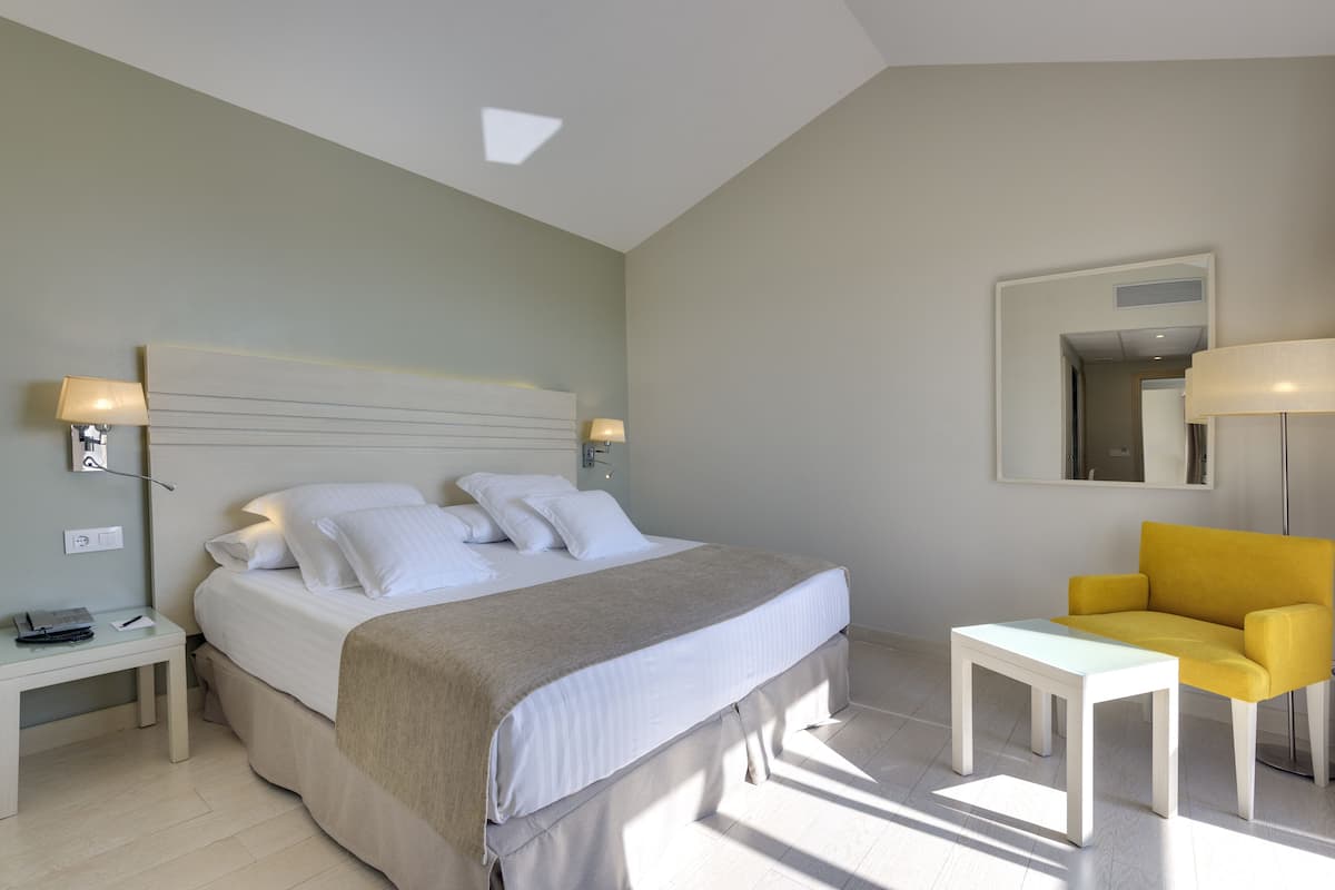 A bedroom with a bed, bedside tables, a chair, and a desk.