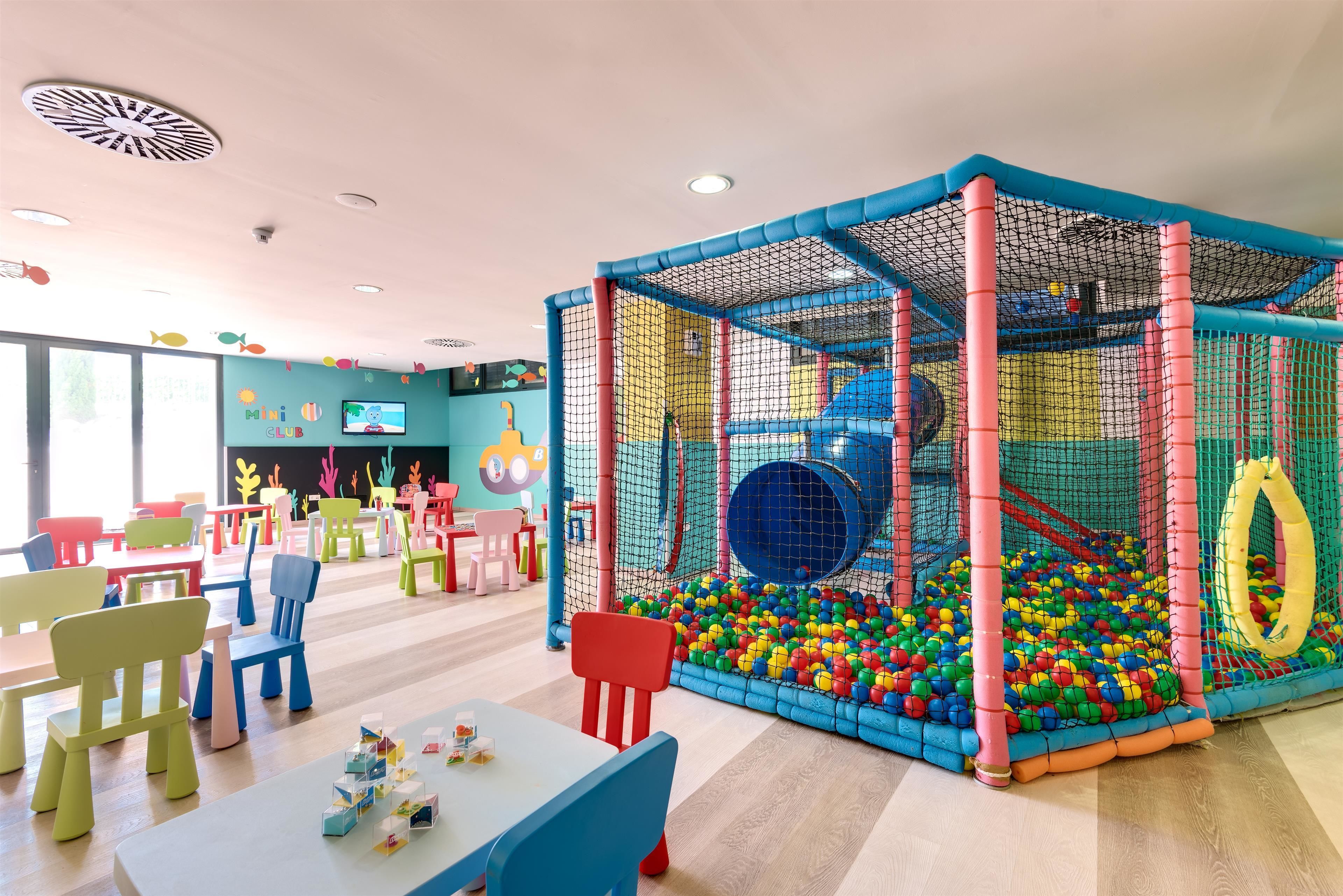 Un área de juegos infantiles con piscina de pelotas y red de escalada.